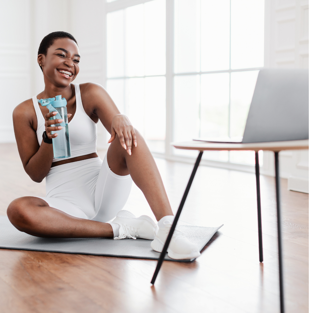 black woman with exercise clothing on drinking water practicing self-care